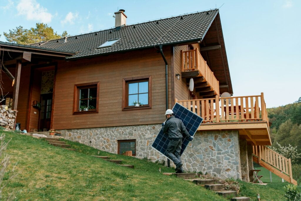 A man carrying a solar panel on stairs, facing challenges for rural electrification.