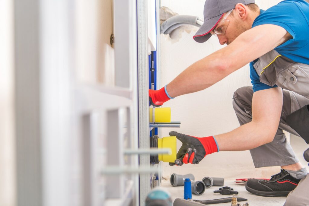 A plumber installing a heat pump hot water system in a bathroom.