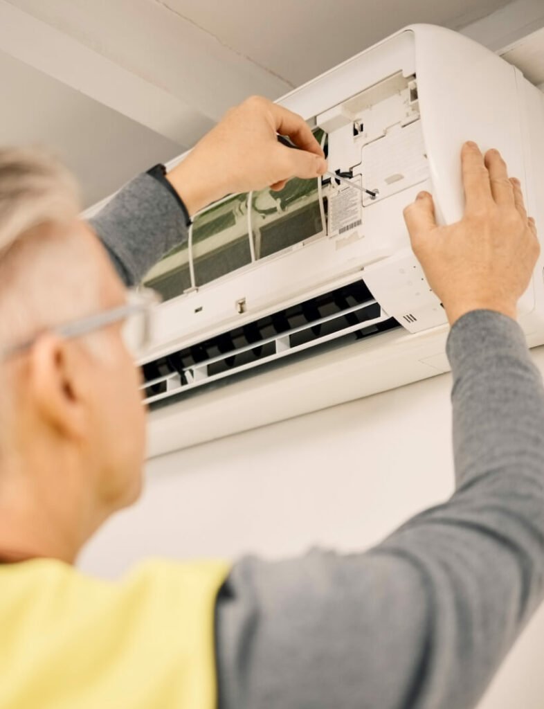 A man is repairing an air conditioner in his home.