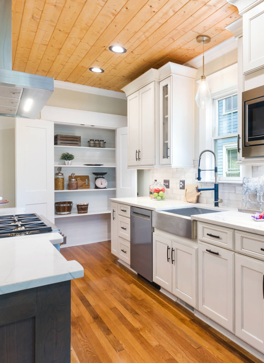 A kitchen with white cabinets and wood floors.